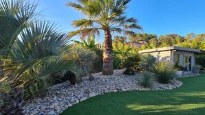A well-maintained garden with palm trees, a small building, and a clear sky. - Villa with pool in a haven of peace (Sommières)
