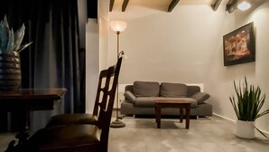 A modern living room with a sofa, a wooden chair, a coffee table, a floor lamp, and a potted plant.