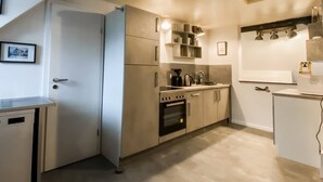 A modern kitchen with a built-in oven, a coffee machine, and a small refrigerator.
