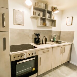 Una cucina moderna con piano cottura integrato, forno e macchina del caffè sul ripiano.