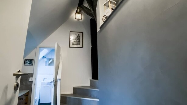 A staircase with a modern design, a small desk with a computer, and a framed picture on the wall.