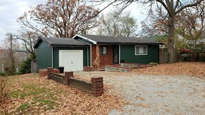 A single-story house with a green exterior, a front garage, and a small front porch. - Cozy Home w/ Doggy Fence (Warsaw)