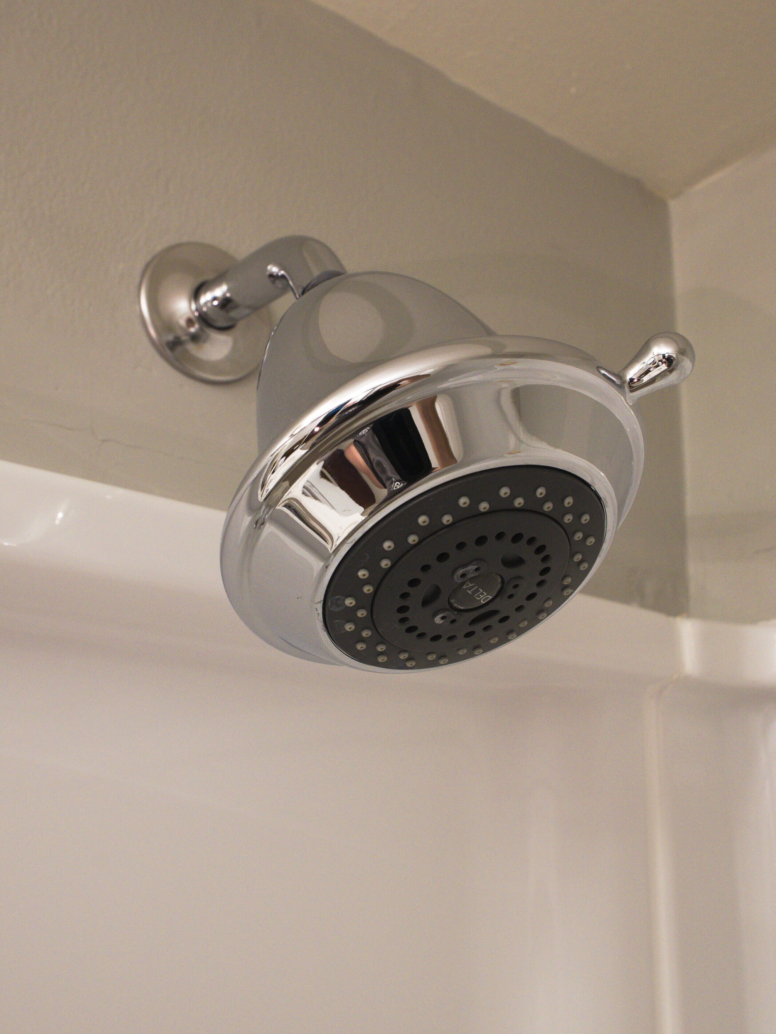 Ein chromfarbener Duschkopf mit rundem, gelochtem Design, an der Wand befestigt.