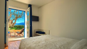 A bedroom with a bed, a nightstand, and a view of an outdoor area with a chair and a table. - House with private garden, pool, jacuzzi and electric bikes (Bordighera)