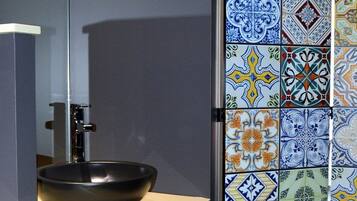 Un baño con un lavamanos moderno y una pared con azulejos.