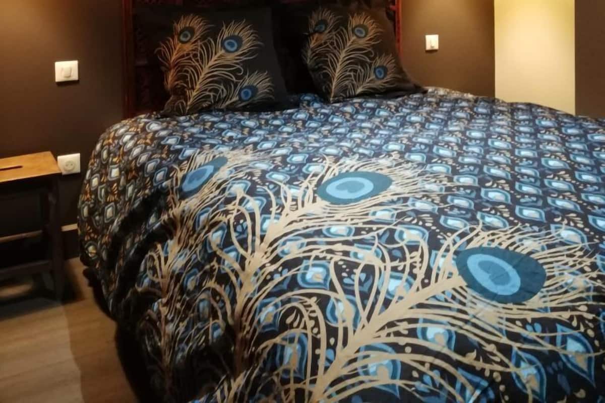Un dormitorio con colcha estampada, almohadas decorativas y dos lámparas colgantes.