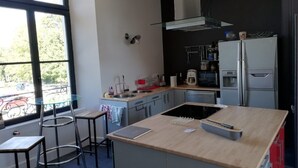 Une cuisine moderne dotée d’un îlot central, d’appareils électroménagers en acier inoxydable et offrant une vue dégagée grâce à de grandes fenêtres.
