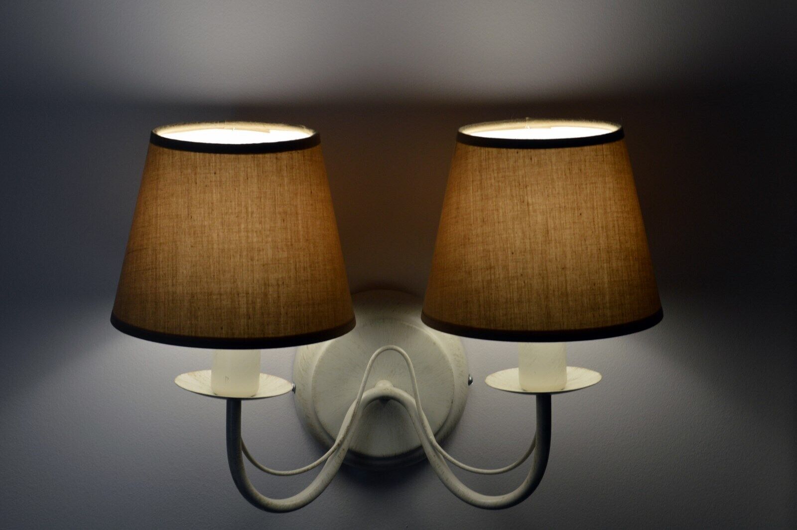 Two wall-mounted lamps with fabric shades on a dark background.