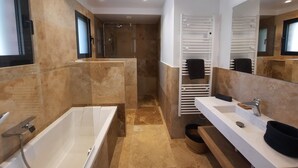 A modern bathroom with a bathtub, a shower, a vanity with a sink, and a towel rack. - Beachfront villa. (Sartène)