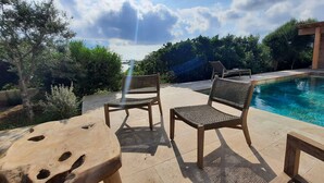 A poolside area with two wicker chairs, a wooden table, and a view of a clear blue pool. - Beachfront villa. (Sartène)