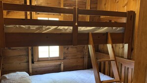 Uma cama beliche com escada em quarto de cabana de madeira.