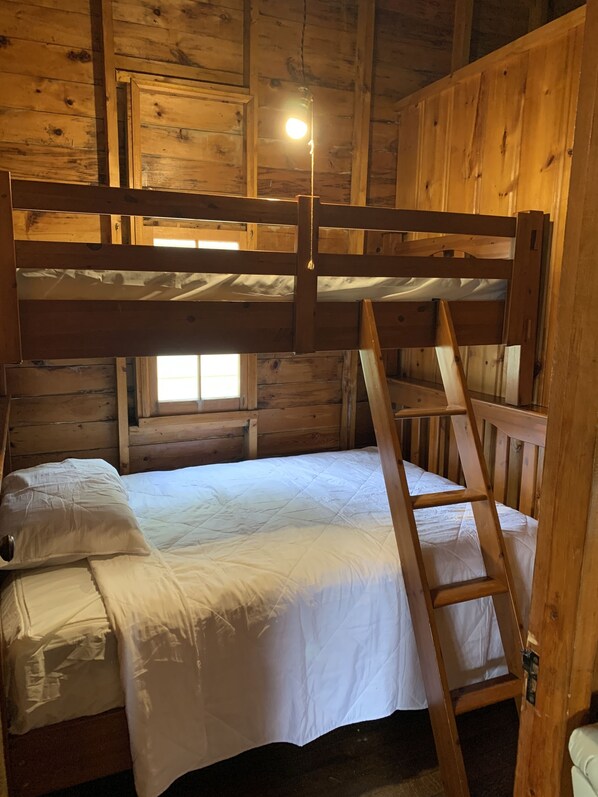 A bunk bed with a ladder in a wooden cabin room.