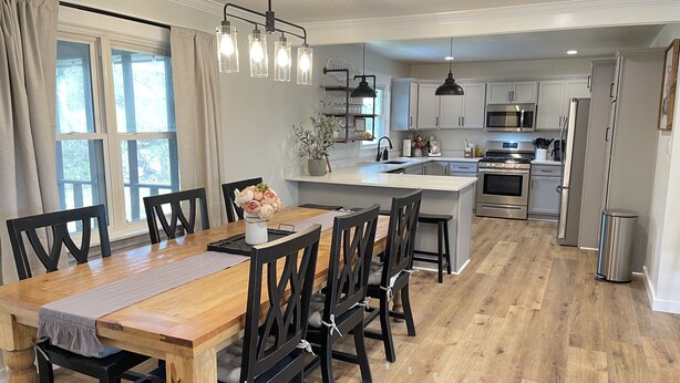 Una cocina moderna con una isla central, una mesa de comedor de madera y sillas negras.