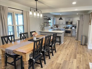 A modern kitchen with a central island, wooden dining table, and black chairs. - Renovated charming home close to Lee University! (Cleveland)