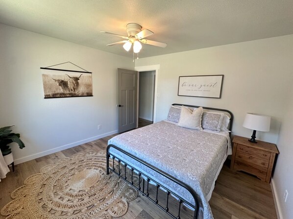 A bedroom with a bed, a bedside table with a lamp, a ceiling fan, a framed picture on the wall, and a decorative rug. - Renovated charming home close to Lee University! (Cleveland)