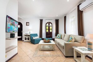 A living room with a television, a sofa, a coffee table, and a lamp. - Private 2BR Villa, Resort Pool, Walkable to Beach (Tamarindo)