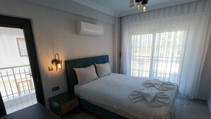 Un dormitorio con cama, mesita de noche, lámpara, aire acondicionado y cortinas.
