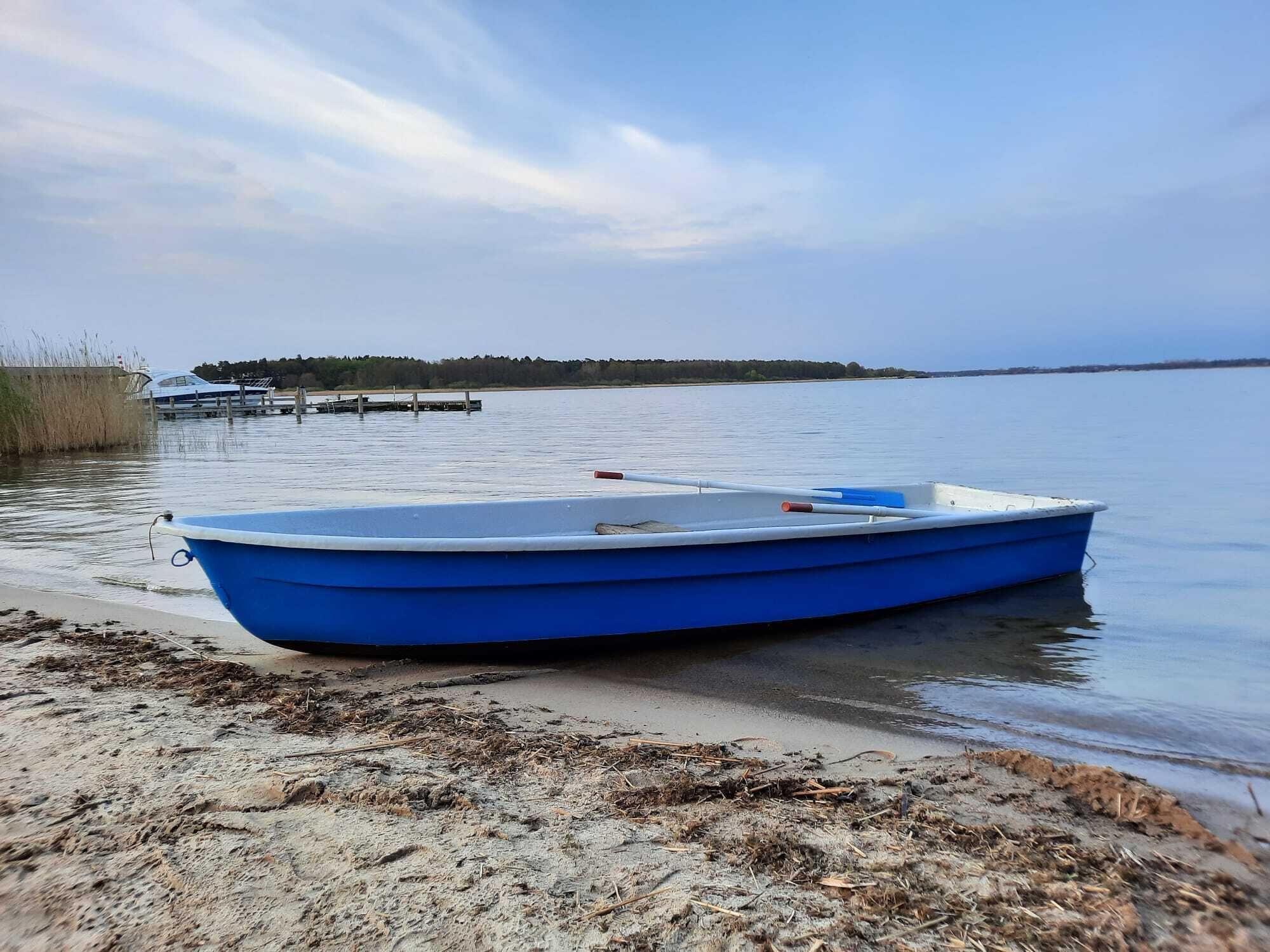 Una pequeña embarcación azul amarrada a un muelle de hormigón al borde del agua.