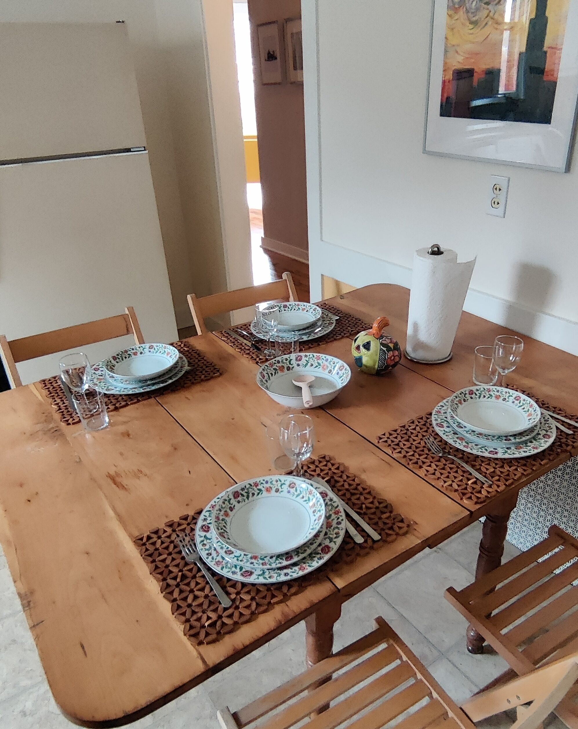 A dining table set with plates, cutlery, and glasses, surrounded by chairs.