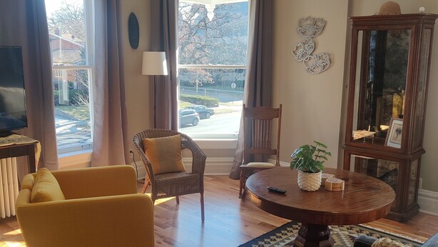 Una sala de estar con sofá, sillas, una mesa redonda de centro y vistas al exterior a través de amplias ventanas.