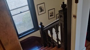 Una escalera de madera con vista a un muro de ladrillo y una ventana.