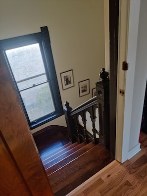 A wooden staircase with a view of a brick wall and a window.