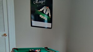 Una mesa de billar con bola blanca y un cartel enmarcado en la pared.