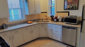 Una cocina con armarios blancos, un microondas, un tostador y un lavabo.