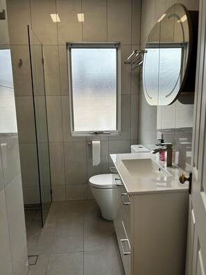 Et moderne badeværelse med toilet, vask og et vindue.