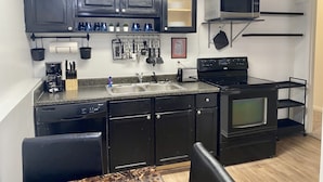 Una cocina compacta con armarios oscuros, microondas, tostadora y cafetera.