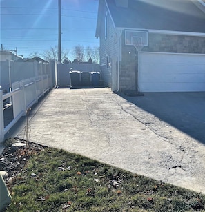 A concrete driveway leading to a garage with a stone wall and a basketball hoop.