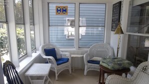 A sunlit room with white wicker furniture, including two chairs with blue cushions and a small table. - Charming 4 Bedroom Cottage in Lakeside w/ 4 person golf cart and linens  (Lakeside Marblehead)