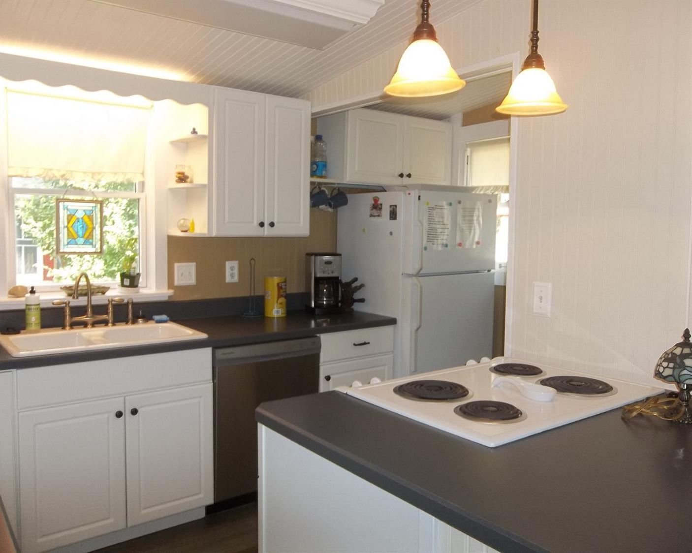 A kitchen with white cabinets, a black countertop, a stove, and a refrigerator.