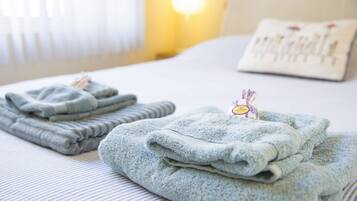 A neatly made bed with folded towels and a visible hotel room sign.