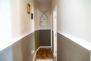 A narrow hallway with wooden flooring, white walls, and a door at the end. - Beautiful 2 Bedroom Apt near PHL Airport/95 (Darby)