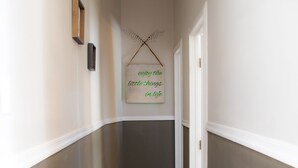 Un pasillo con suelo de madera, alfombra estampada y un cartel en la pared.
