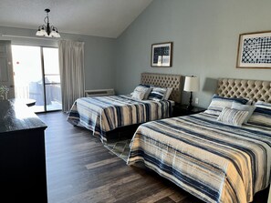 Habitación de hotel con dos camas, un escritorio y vistas al exterior.