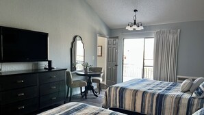Quarto de hotel com duas camas, televisão, escrivaninha e varanda.
