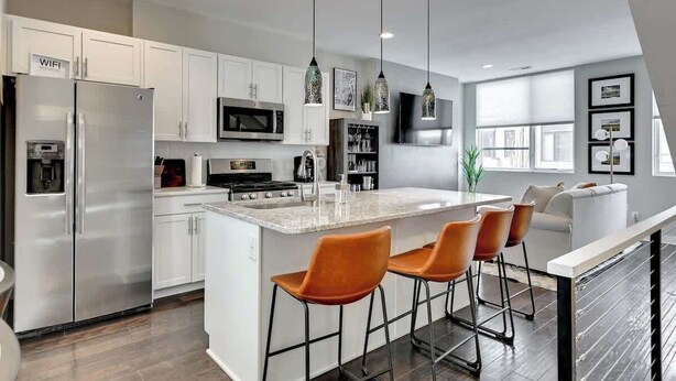 A modern kitchen with white cabinets, stainless steel appliances, and a central island with bar stools.