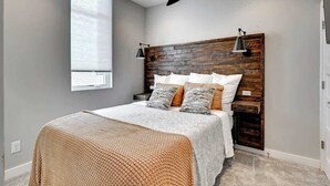 A bedroom with a bed, a wooden headboard, a window, and a lamp.