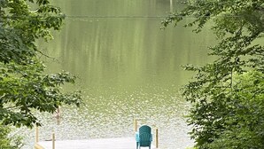 Ein Rasen mit einem Steg, einer Reihe von Stühlen und einem kleinen Teich.