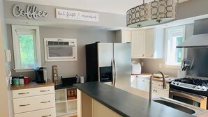 Eine moderne Küche mit weißen Schränken, einem Einbauherd und einer Kaffeestation.