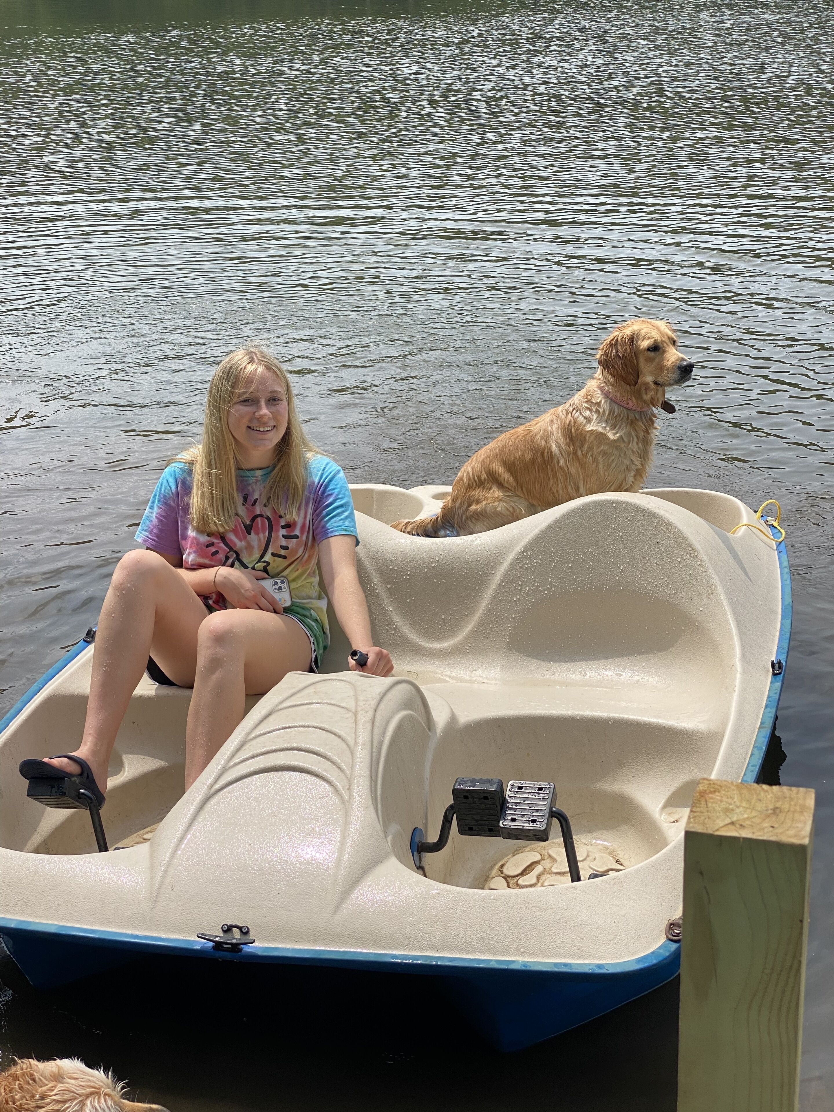 A person and a dog in a small boat on water.