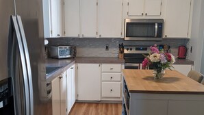 Une cuisine moderne avec des armoires blanches, des appareils en acier inoxydable et un plan de travail en bois.