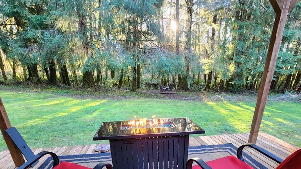 Une terrasse extérieure avec une table à plateau de verre et deux chaises rouges dotées de coussins.