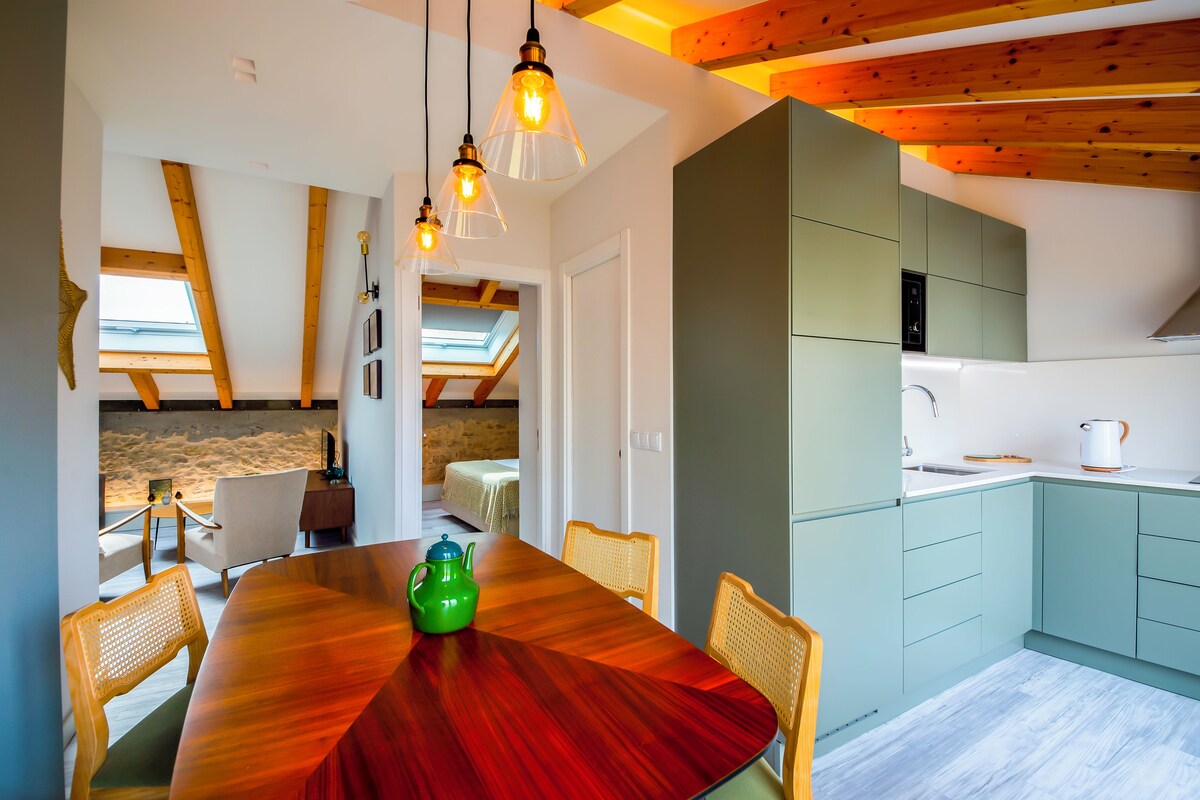 Un interior moderno con comedor, cocina y una habitación loft con tragaluces.