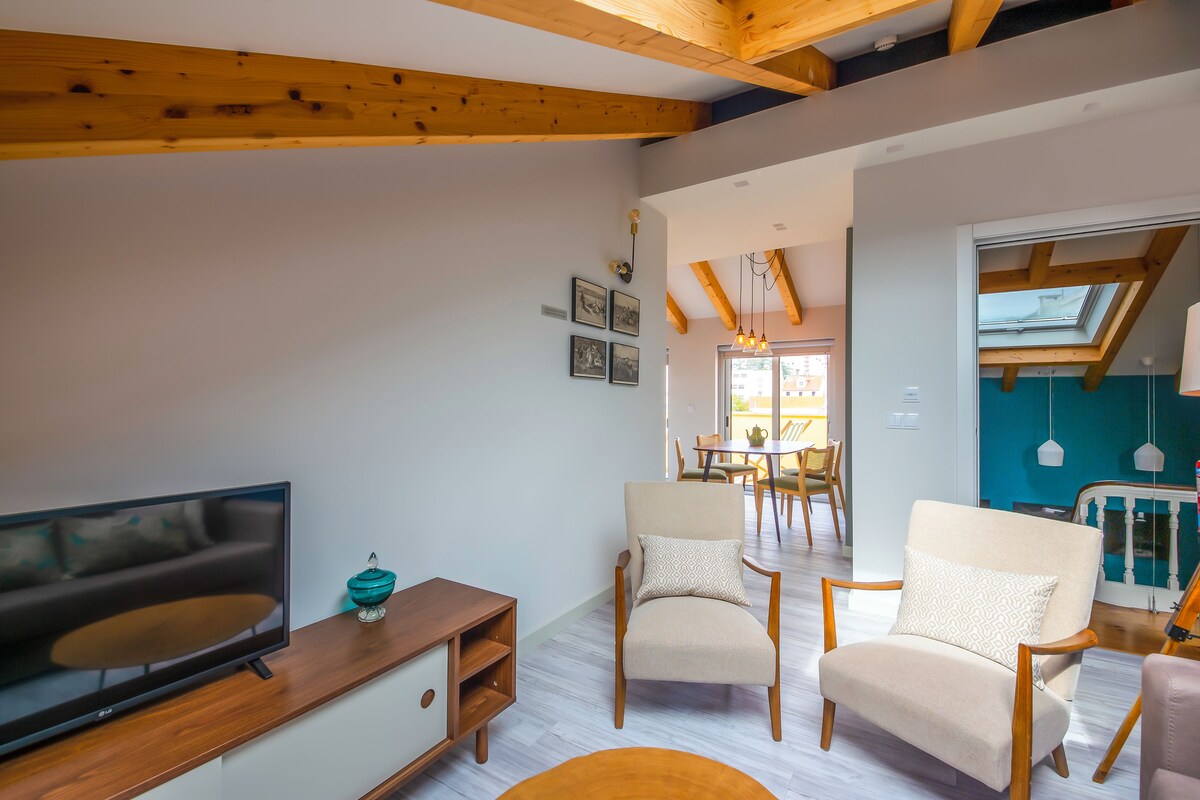 A modern living room with a TV, wooden furniture, and a dining area in the background.