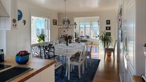 A spacious dining area with a large table and chairs, surrounded by windows and a chandelier. - Gorgeous home in Fjell with WiFi (Fjell)
