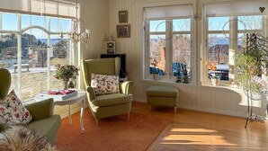 A cozy room with a large window, a green armchair, a small table, and a television. - Gorgeous home in Fjell with WiFi (Fjell)
