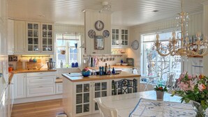 A spacious kitchen with white cabinetry, a central island, and a dining area with a table and chairs. - Gorgeous home in Fjell with WiFi (Fjell)